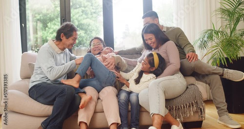 Loving family enjoying time together, bonding and with granny, grandpa and parents tickling smiling child. Adorable little girls playing with their grandparents, laughing in the home living room. photo