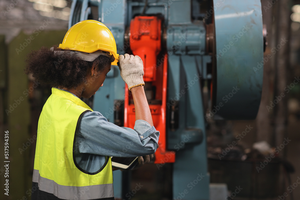 Technician engineer or worker in protective uniform standing and holding tablet while controlling operation or checking industry machine process with hardhat at heavy industry manufacturing factory Technician engineer or worker in protective uniform standing and holding tablet while controlling operation or checking industry machine process with hardhat at heavy industry manufacturing factory