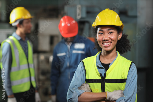 Confident technician engineer woman in protective suit standing and arms cross while looking camera and maintenance operation work lathe metal machine at heavy industry manufacturing factory