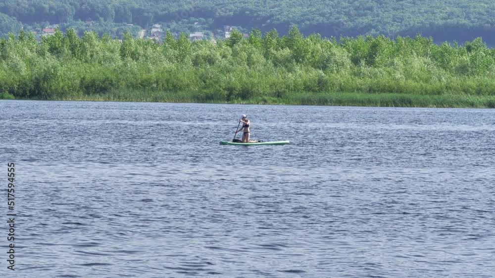 A girl rides on an inflatable board on a river on a summer day . Sports and recreation. Lifestyle. A girl rides on an inflatable board on a river on a summer day . Sports and recreation. Lifestyle.