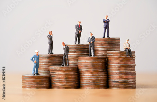 Fotografiet Many Business miniature figure standing on coins stacking for different income and salary in each position