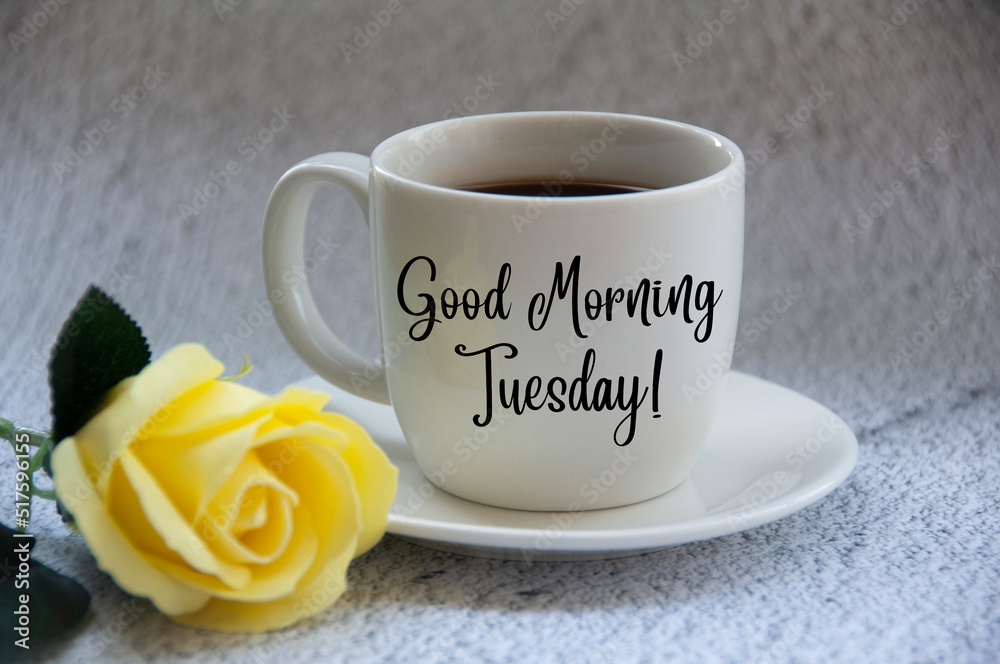 Good morning Tuesday text on coffee cup yellow flower on blurred