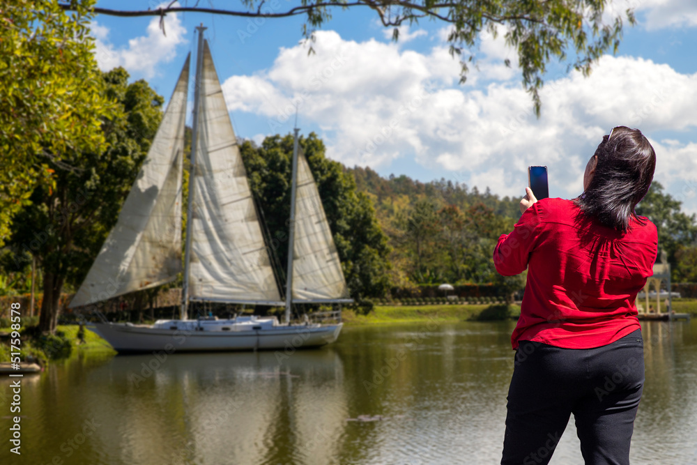 Fototapeta premium woman takes a photo of sailboats anchored in the bay. with mobile phone