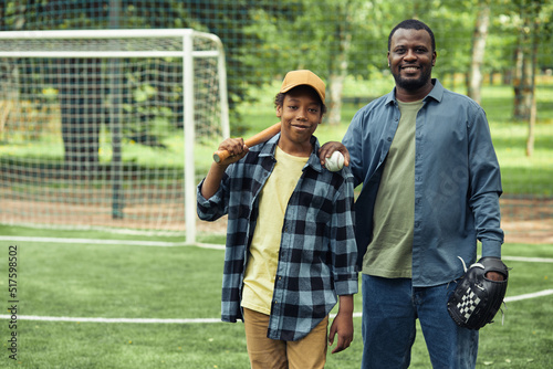 Photography Portrait of father and son with glove and bat standing on baseball field and smi