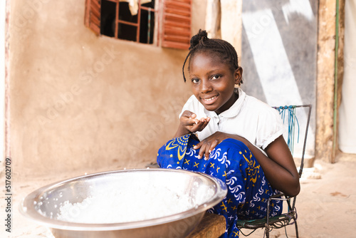 Poor African girl eating white rice without dressing, vegetables or meat; importance of staple food such as bread, rice and potatoes in developing countries photo