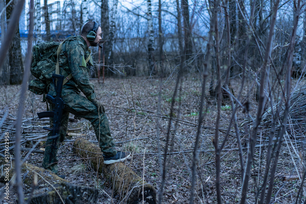 soldier in the forest. a man in military uniform in the branches of trees, in an ambush with a weapon, rifle or machine gun. military actions. airball game