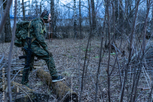 soldier in the forest. a man in military uniform in the branches of trees  in an ambush with a weapon  rifle or machine gun. military actions. airball game