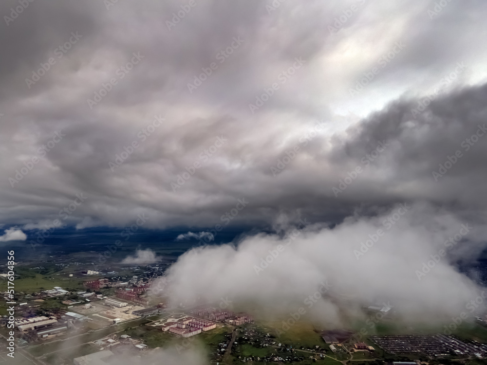 Fototapeta premium Flying through thick clouds. Rain clouds in the sky. Cumulus clouds, meteorology and climate studies.Photo of the city from the height of clouds, aerial photography.Quadcopter,drone