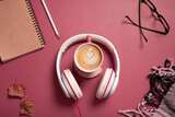 Creative flat lay composition with coffee cup and headphones on dark pink color background. Creative music, relax, online concept