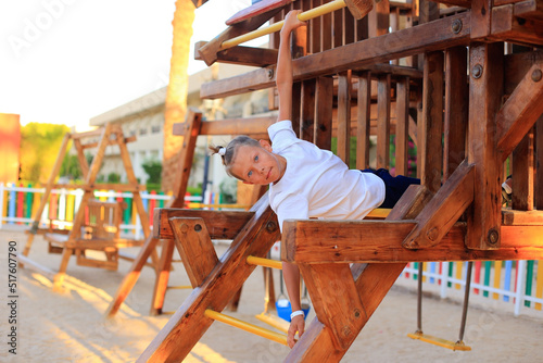 The girl rides on a swing in the playground. Children s outdoor carousels