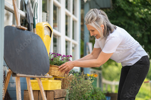 A woman in white thsirt spending time in the graden and looking busy photo