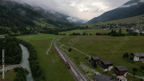 Domestic train moving in Swiss valley on cloudy summer day. Drone footage. photo