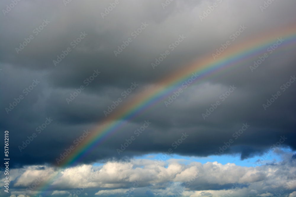 Rainbow arching against gray storm clouds Rainbow arching against gray storm clouds
