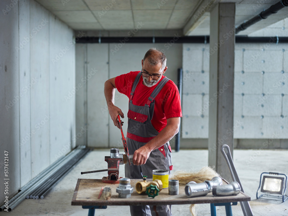 Mature plumber cutting metal pipe on workbench Mature plumber cutting metal pipe on workbench