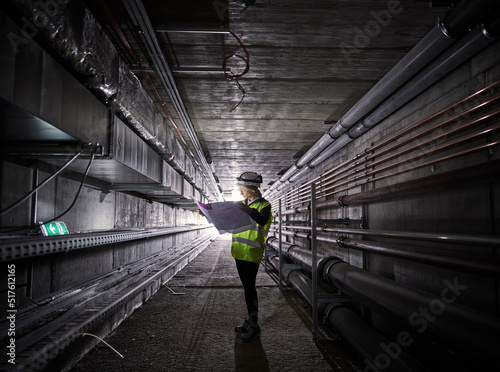 Young engineer looking at blueprint standing in tunnel photo