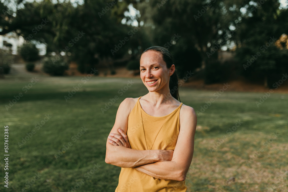 Happy woman with arms crossed standing at park Happy woman with arms crossed standing at park