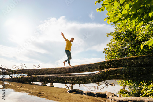 Man walking on fallen tree at lake photo