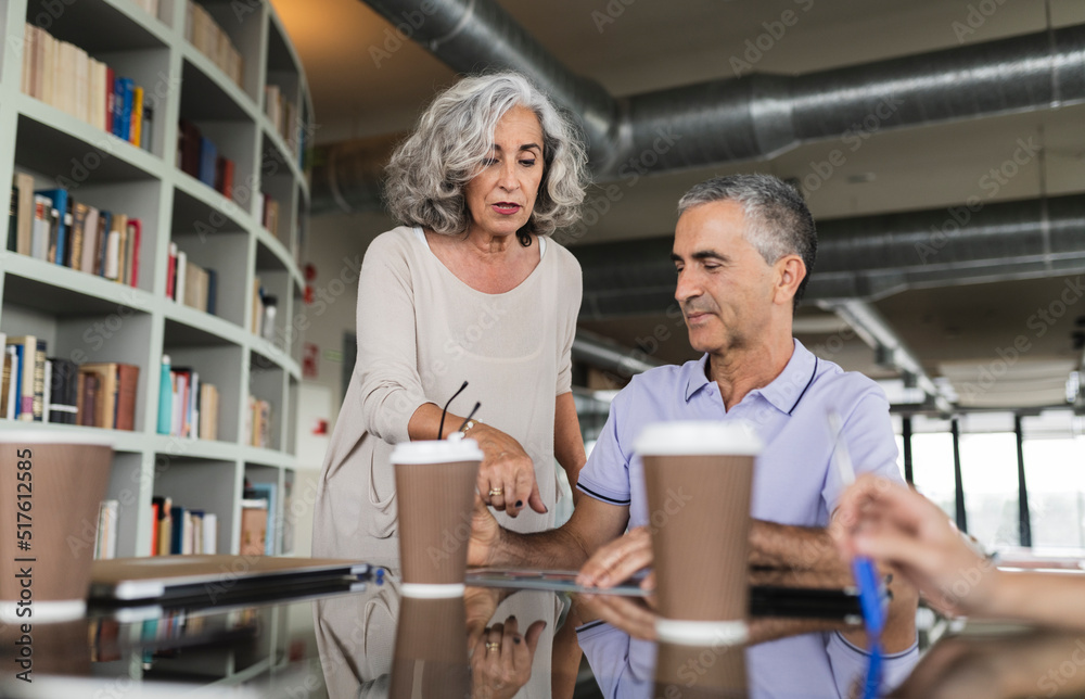 Senior businesswoman discussing with businessman in office Senior businesswoman discussing with businessman in office