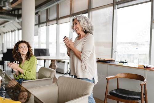 Senior businesswoman with young colleague clapping in office