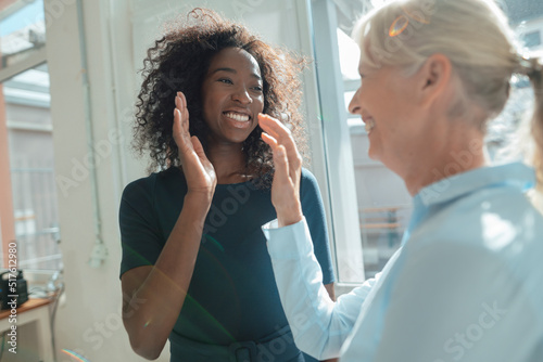 Smiling businesswoman giving high-five to colleague in office