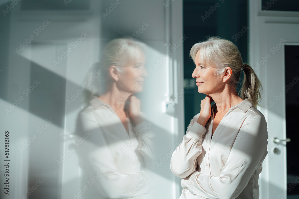 Smiling businesswoman looking through window in office Smiling businesswoman looking through window in office
