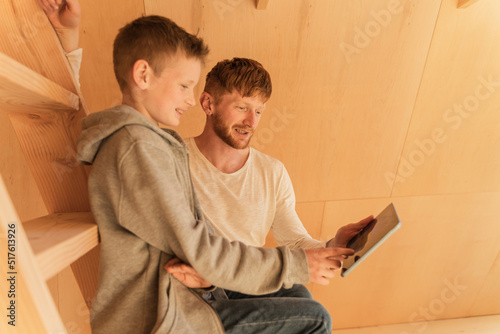 Father and son using tablet pc for creating home interior in eco wooden house photo