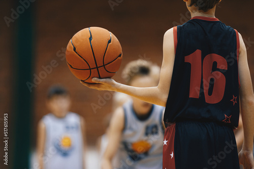 Young basketball player with classic ball. Junior level basketball player holding game ball. Basketball training session for kids © matimix