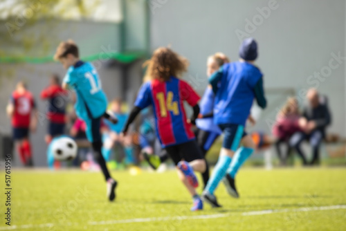 Blurred image of children football match. Kids play football on outdoor field. Children score a goal at soccer game. School sports tournament background