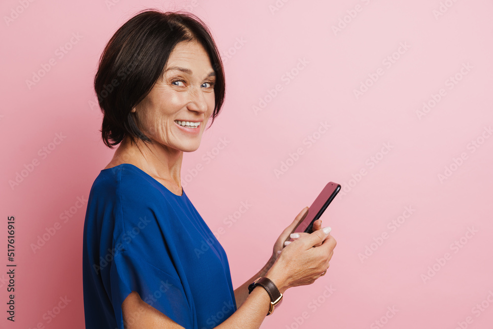 Mature brunette woman smiling and using mobile phone Mature brunette woman smiling and using mobile phone