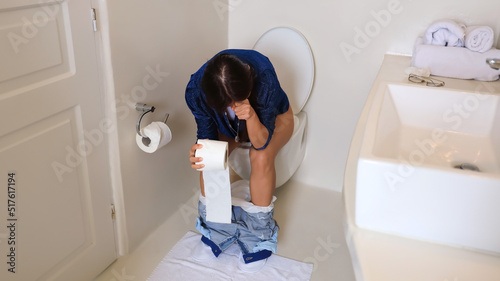 Selective focus of woman hand with a paper roll which She is carpopedal spasm hand and constipation in a toilet.