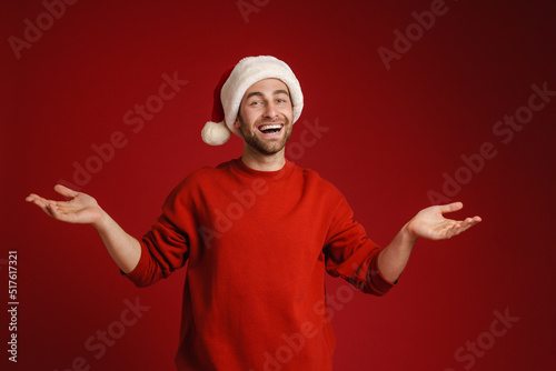 Young smiling man wearing santa hat holding copyspace
