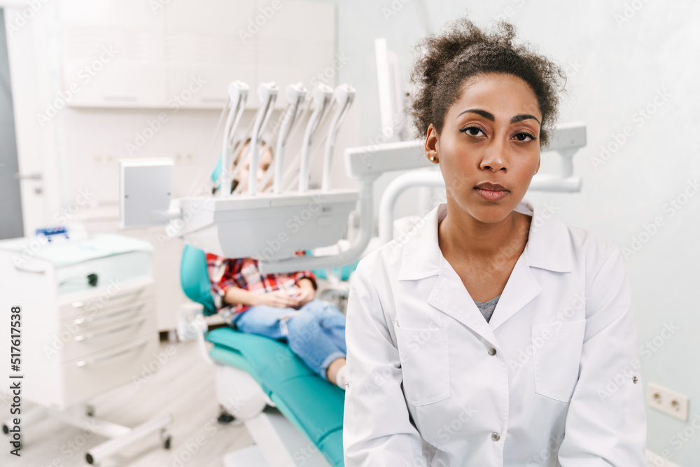 Black dentist wearing lab coat working with patient in clinic Black dentist wearing lab coat working with patient in clinic