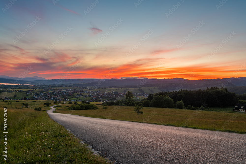 Road running through mountain landscape during spectacular sunset