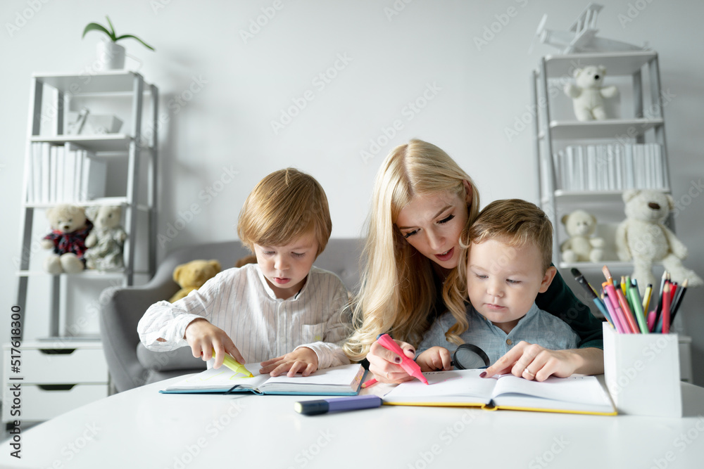 Teacher helping school child in class at school. Little children with kindergarten teacher drawing at table indoors. Learning and playing. Children drawing in kindergarten. Teacher helping school child in class at school. Little children with kindergarten teacher drawing at table indoors. Learning and playing. Children drawing in kindergarten.
