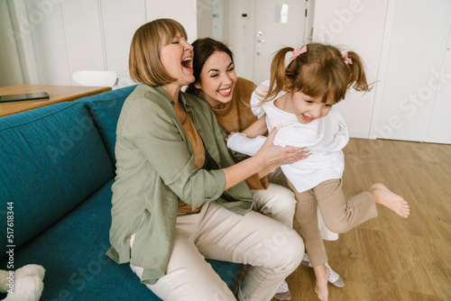 White girl playing with her mother and granddaughter on couch