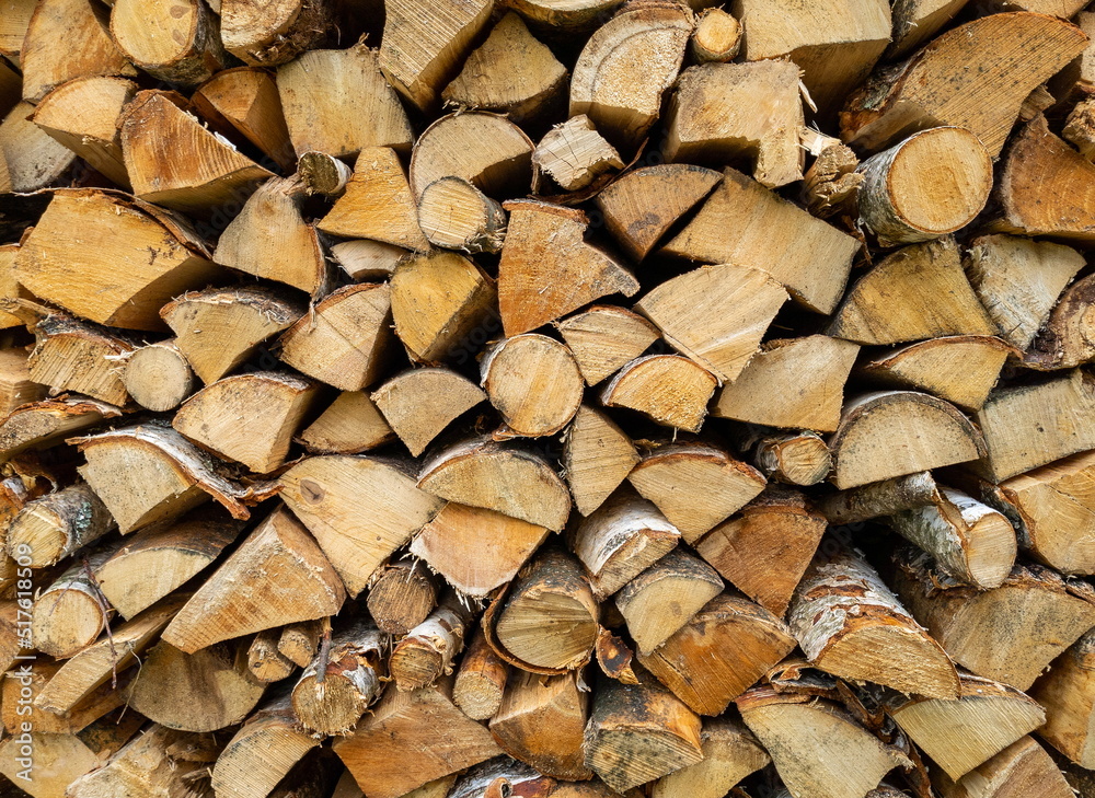 Dry birch firewood stacked in a neat woodpile. A supply of wood for kindling the fireplace. Wooden texture. Dry birch firewood stacked in a neat woodpile. A supply of wood for kindling the fireplace. Wooden texture.