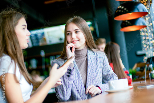 Two girls have a cheerful talk with cup of coffee.