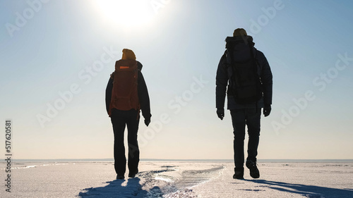 The two tourists with backpacks traveling through the snow field photo