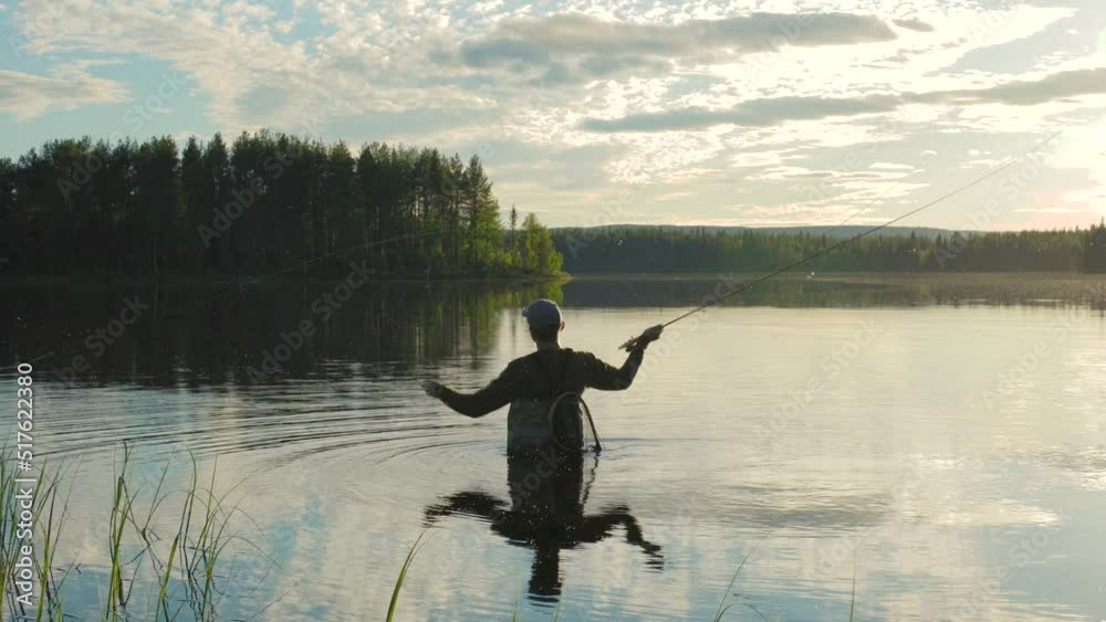 At sunset in the lake, a man is fly-fishing in the river. Fly fishing. At sunset in the lake, a man is fly-fishing in the river. Fly fishing.