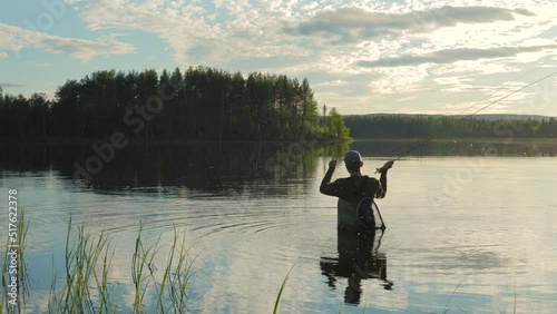 At sunset in the lake, a man is fly-fishing in the river.