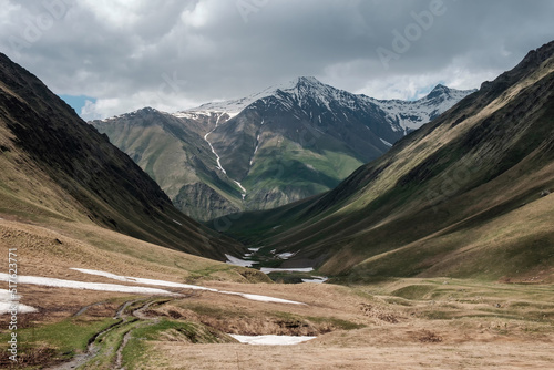 Georgia, Caucasus Mountains, Juta valley - cold river, dark shadows, mountain from stones and snowy peak Chaukhebi in summer.