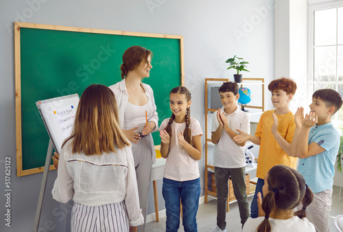 Learning while playing. Children in primary school in creative lesson learn by playing games together with teacher. Friendly female teacher and schoolchildren in classroom clapping their hands.