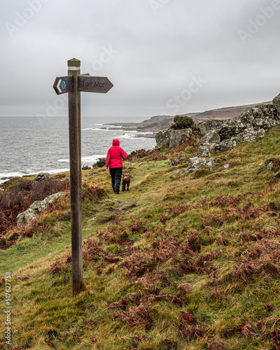 A lady in red walking her dog on Blane Way in Bute Scotland on a wet day photo