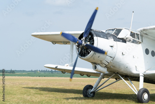 An An-2 airplane starts its engine on the grass airfield. The propeller starts rotating. Front view.