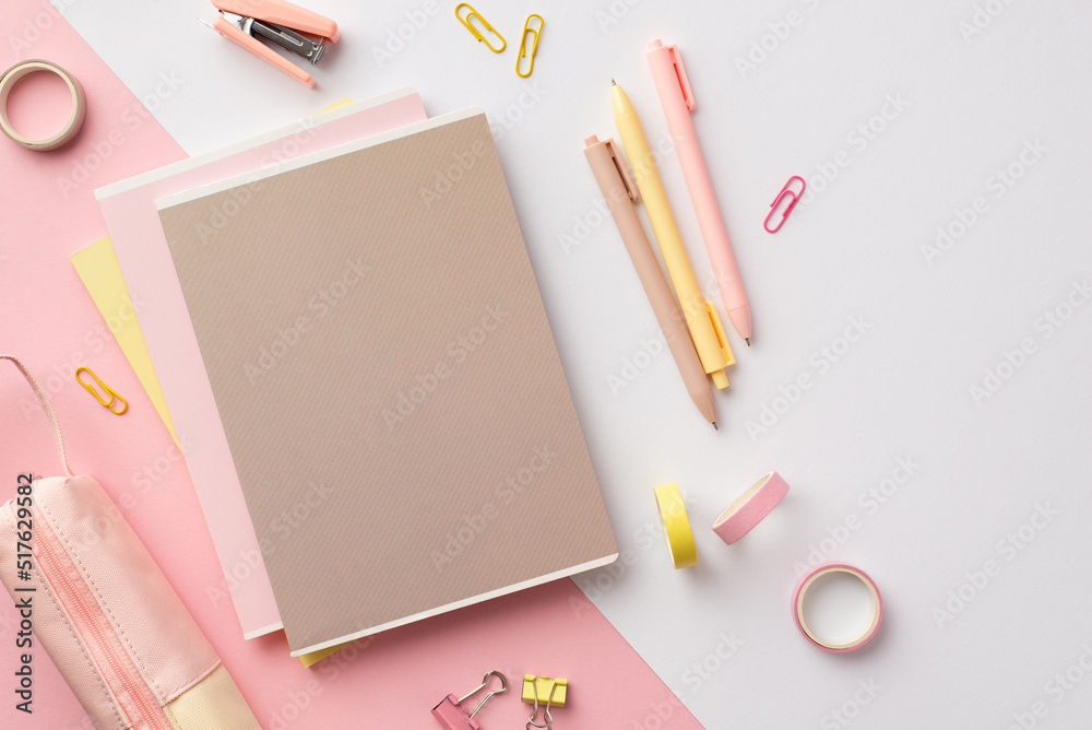School accessories concept. Top view photo of pink and yellow stationery diaries pens mini stapler binder clips adhesive tape and pencil-case on bicolor pink and white background School accessories concept. Top view photo of pink and yellow stationery diaries pens mini stapler binder clips adhesive tape and pencil-case on bicolor pink and white background