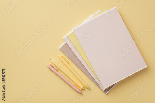 Back to school concept. Top view photo of notebooks and pens on isolated pastel yellow background