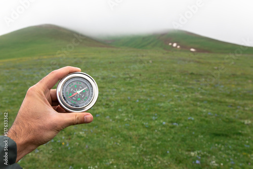 holding compass on green landscape background