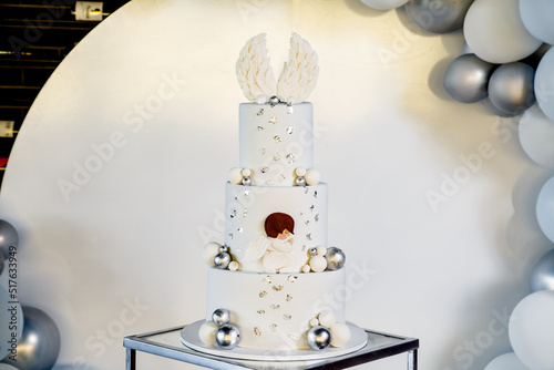 Obraz na płótnie White christening cake with angel wings on top in banquet hall with the balloons behind w salonie