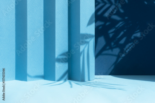 Abstract blue background with shadow of palm leaves for the presentation of a cosmetic product. A scene with a geometric backdrop. Podium for product promotion, beauty, natural eco cosmetic. Showcase.