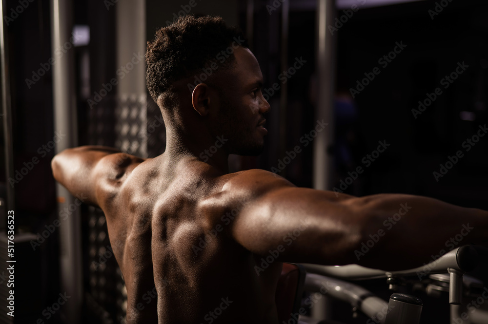 Shirtless african american man doing back exercises on a machine in the gym. Shirtless african american man doing back exercises on a machine in the gym.